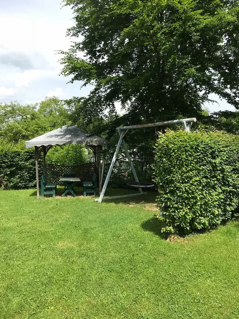 Gartenbereich von Camping Wallersee - Stacaravans Salzburg mit Schaukel, Pavillon und viel Grün.