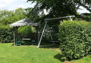 Espace vert au Camping Wallersee - Stacaravans Salzburg avec balançoire, tonnelle et verdure luxuriante.