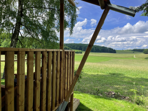 Blick von der Glamping-Unterkunft bei Camping Azur Sonnenbühl - Nature Lodge Baden-Württemberg auf grüne Felder.