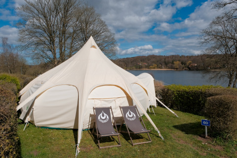 Grote lodgetent met twee ligstoelen aan het meer bij Natuurpark Camping Prinzenholz, Sleeswijk-Holstein.