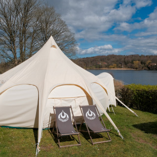 Großes Glamping-Zelt mit zwei Liegestühlen vor dem Zelt am See im Natuurpark Camping Prinzenholz, Schleswig-Holstein.