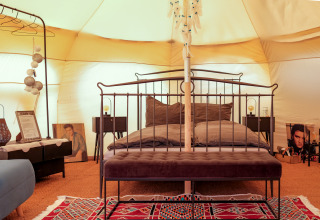 Intérieur d’une tente glamping au Natuurpark Camping Prinzenholz avec lit double et ambiance chaleureuse.