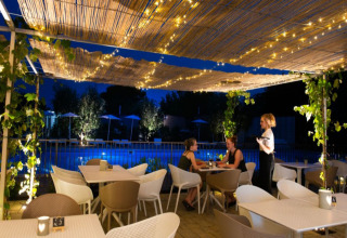 Terrasse extérieure éclairée avec guirlandes au Vacanze Glamping Boutique près du lac de Garde, en soirée.