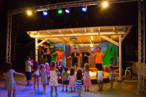 Des enfants assistent à un spectacle en soirée lors du glamping Vacanze col Cuore près du lac de Garde.