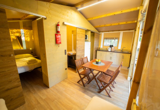 Innenansicht eines luxuriösen Glamping-Zeltes mit Holzmöbeln, Schlafzimmer, Küche und Essbereich.