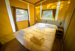 Glamping accommodatie van Vacanze col Cuore: comfortabele lodgetent met bed en uitzicht op het bos bij Gardameer