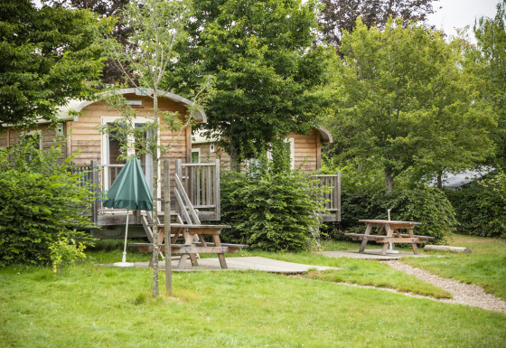 Holzhütten und Picknicktische im Grünen bei Huttopia Etang de Fouché Glamping Bourgogne, Frankreich.