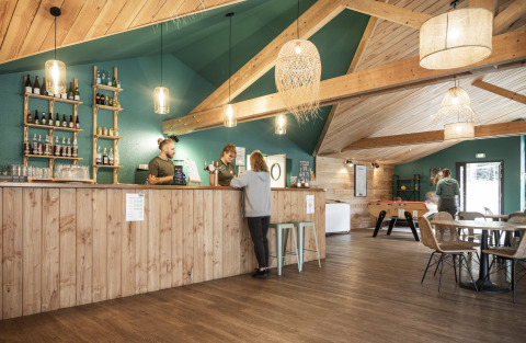 Interieur bar en lounge van Huttopia Etang de Fouché - Glamping Bourgogne met houten wanden en warme verlichting.