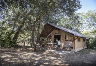 Personnes profitant du glamping à Huttopia Forêt de Janas - Glamping Côte d’Azur, terrasse au milieu des arbres.