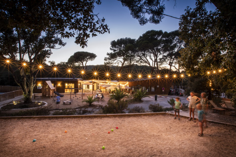 Evening scene at Huttopia Forêt de Janas - Glamping Côte d’Azur with string lights, children and playground.
