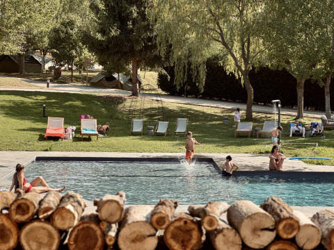 Familien entspannen am Pool von Basecamps - Cabins Girona, einem Glampingplatz mit Zelten im Grünen.