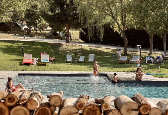 Famiglie si rilassano nella piscina di Basecamps - Cabins Girona, un glamping con tende immerso nella natura.