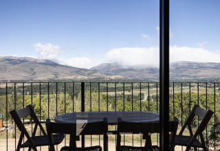 Vista da Basecamps - Cabins Girona: tavolo e sedie su terrazza con panorama sulla valle e le montagne.