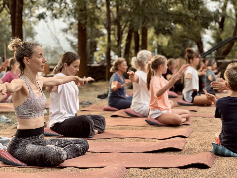 Personas practicando yoga al aire libre en Basecamps - Cabins Girona, disfrutando de alojamiento glamping.