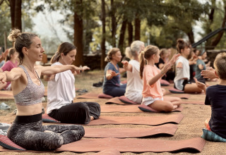 Persone che praticano yoga all'aperto a Basecamps - Cabins Girona, soggiorno glamping eco-chic.