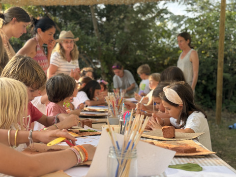 Kinderen doen creatieve activiteiten buiten bij Basecamps - Cabins Girona, een glamping-accommodatie in de natuur.