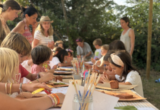 Kinderen doen creatieve activiteiten buiten bij Basecamps - Cabins Girona, een glamping-accommodatie in de natuur.