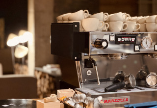 Espressomaskine med stablede kopper i Basecamps - Cabins Girona, hyggelig camping og glamping oplevelse.