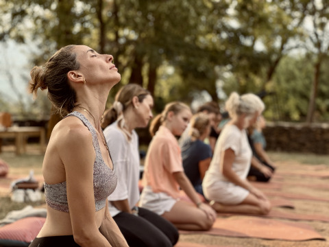 Personas haciendo yoga al aire libre en Basecamps - Cabins Girona, rodeadas de naturaleza tranquila y verde.