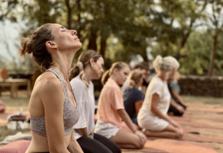 A group practicing outdoor yoga on mats at Basecamps - Cabins Girona, enjoying peaceful natural surroundings.