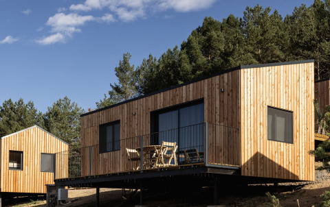 Moderne glamping hytter ved Basecamps - Cabins Girona, omgivet af skov og natur under blå himmel.