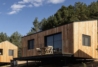 Moderne glamping hytter ved Basecamps - Cabins Girona, omgivet af skov og natur under blå himmel.