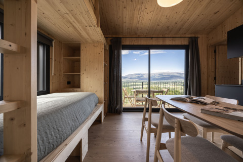 Moderne glamping-hytte fra Basecamps - Cabins Girona med træinteriør og udsigt til bjergrige landskaber.