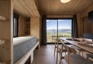 Alloggio glamping Basecamps - Cabins Girona con interni in legno e grandi finestre affacciate sulle montagne.