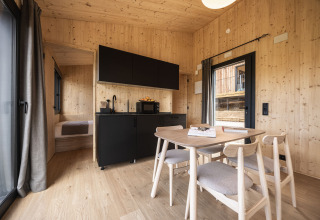 Gemütliche Glamping-Unterkunft bei Basecamps - Cabins Girona mit Holzwänden, Küchenzeile und Tisch.
