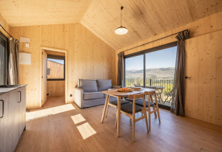 Interieur van Basecamps - Cabins Girona glamping, licht houten inrichting met uitzicht op bergen en balkon.