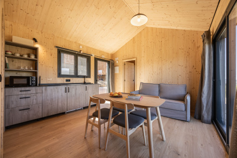 Modern houten interieur bij Basecamps - Cabins Girona met eettafel, bank en keukenblok.