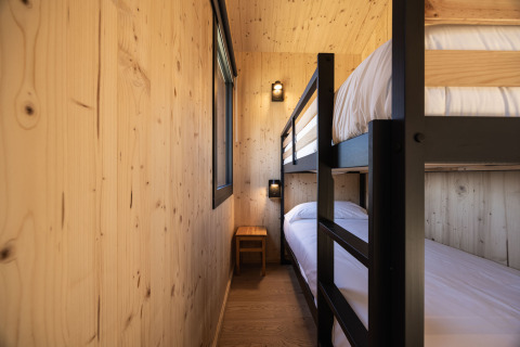 Cabina glamping moderna a Basecamps - Cabins Girona con letti a castello e pareti in legno chiaro.