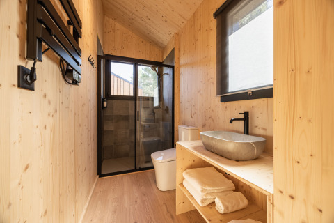 Bagno moderno rivestito in legno presso Basecamps - Cabins Girona, ideale per un'esperienza di glamping.