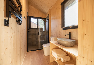 Modern wood-paneled bathroom at Basecamps - Cabins Girona, perfect for a comfortable glamping experience.