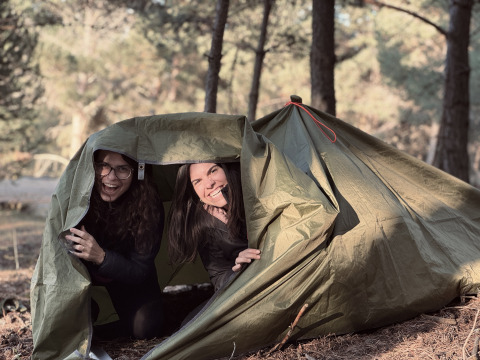 Two women enjoying their camping adventure at Basecamps - Cabins Girona, smiling outside a green tent.