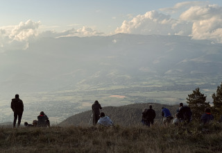 En gruppe mennesker nyder udsigten over dalen og bjergene ved Basecamps - Cabins Girona under en klar himmel.