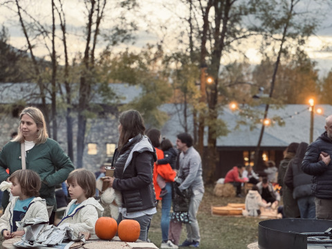 Buitenscène bij Basecamps - Cabins Girona: gezinnen met kinderen, pompoenen en een kampvuurplek.