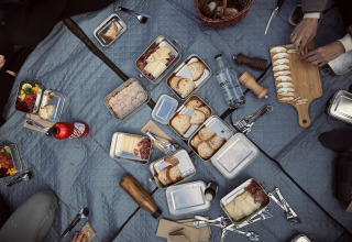 Udendørs picnic på et tæppe med diverse madvarer, brød, ost og frugt hos Basecamps - Cabins Girona.