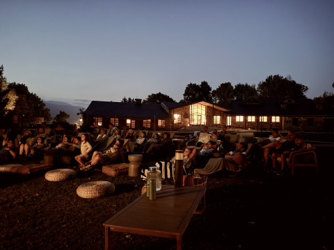 Séance de cinéma en plein air le soir à Basecamps - Cabins Girona avec des invités assis confortablement.
