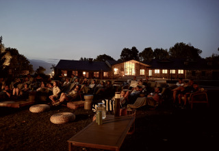 Udendørs biografoplevelse om aftenen ved Basecamps - Cabins Girona med gæster på komfortable møbler.