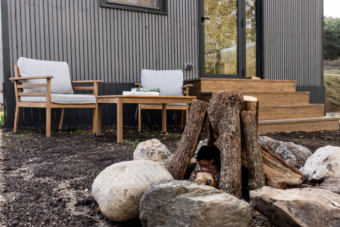 Area relax esterna con sedie di legno e falò ai Basecamps - Cabins Girona vicino a una cabina moderna.