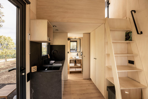 Interno di Basecamps - Cabins Girona glamping, con cucina moderna, scala e bagno accogliente.