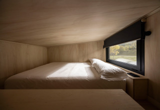 Interieur van Basecamps - Cabins Girona glamping, bed bij raam met natuurzicht in gezellige houten cabine.