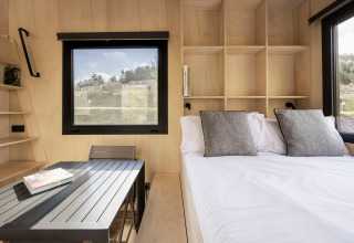 Modern Basecamps - Cabins Girona glamping accommodation with bed, dining table and large windows.