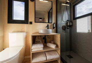 Modern badkamerinterieur bij Basecamps - Cabins Girona met douche, toilet, wastafel en verse handdoeken.