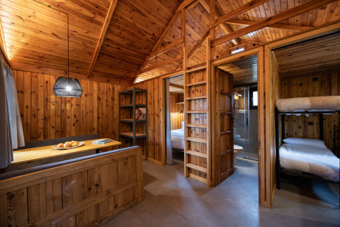 Interieur van een houten cabin bij Basecamps - Cabins Girona met stapelbed, slaapkamer en eetgedeelte voor glamping.