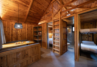 Interior of a wooden cabin at Basecamps - Cabins Girona with bunk beds, bedroom, and dining area for glamping.