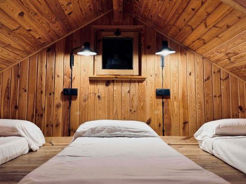 Hyggelig trækabine med tre senge og balkonvægge, Basecamps - Cabins Girona, ideelt til glamping.