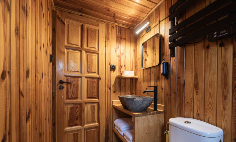 Bagno in stile moderno presso Basecamps - Cabins Girona, con interni in legno, lavabo in pietra e atmosfera glamping.