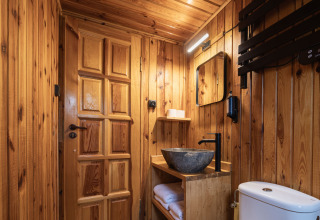 Moderne badkamer bij Basecamps - Cabins Girona, met houten interieur, stenen waskom, spiegel en toilet.